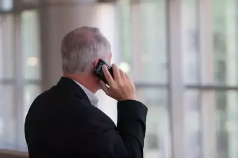 Ein Mann steht mit der Rückenansicht mit einem Smartphone in der Hand